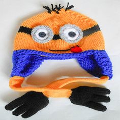 an orange and blue knitted hat with googly eyes on top of a pair of black gloves