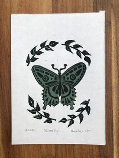 a drawing of a butterfly sitting on top of a piece of paper with leaves around it