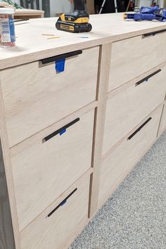 a close up of a wooden dresser with drawers and tools on the counter top,