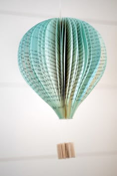 an origami hot air balloon hanging from a string with books on the strings