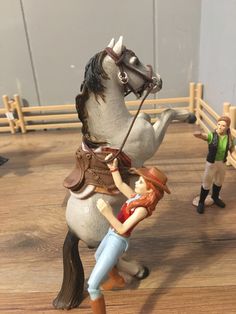 two toy figurines, one holding the reins of a horse