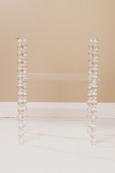 two clear acrylic vases sitting on top of a white floor next to a wall