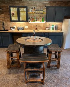 a kitchen table with stools around it and bottles on the counter top in the background