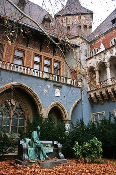 an old building with a statue in front of it and lots of leaves on the ground