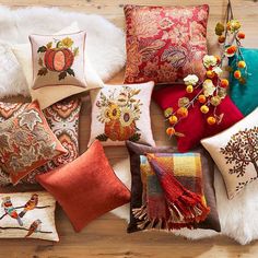 a collection of decorative pillows on a wooden floor with fur and pom - poms