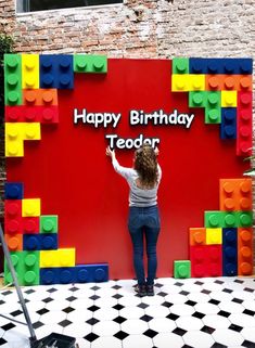 a woman standing in front of a birthday sign made out of legos