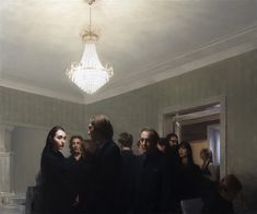 a group of people standing in a room next to a chandelier hanging from the ceiling