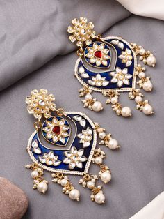 These crescent-moon shaped dark blue kundan earrings are the perfect match for any festive outfit, especially when you want to add that extra hint of glamour! They feature a red centre stone to bring a beautiful contrast to the overall look. The earrings have a push-back closure and are comfortable to wear for long durations.  This earring design is also available in a gorgeous pink and a festive yellow colour to brighten up your outfits! Blue Kundan Chandbalis For Celebration, Blue Temple Jewelry Chandbalis For Celebration, Traditional Blue Chandbalis For Wedding, Blue Chandbali Chandelier Earrings For Party, Blue Chandbali Chandelier Earrings For Wedding, Traditional Blue Chandelier Earrings For Party, Festival Blue Kundan Chandbalis, Blue Kundan Chandbalis For Festivals, Blue Kundan Chandbalis With Meenakari