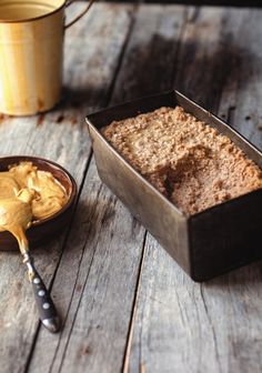 a pan filled with cake next to a bowl of peanut butter on a wooden table