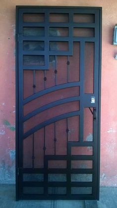 an iron gate is shown against a pink wall