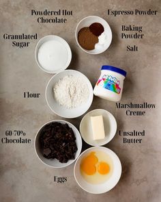 ingredients to make chocolate cake laid out in bowls on top of a stone countertop