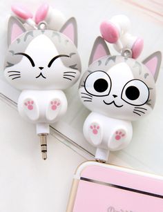 two cute cat shaped usb devices sitting on top of a table next to a pink phone