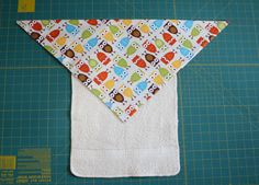 an oven mitt made out of fabric with owls and cars on it, sitting on top of a cutting board