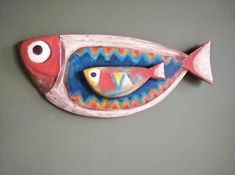 a ceramic fish with two eyes on it's side, sitting on a gray surface