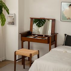 a bedroom with a bed, desk and mirror in it's corner area next to a potted plant