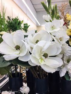 white and yellow flowers in black vases on display