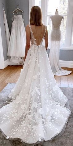 the back of a woman's wedding dress in front of a window and mannequins