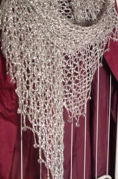 a crocheted shawl hanging from the side of a bed with red drapes