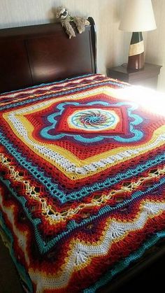 a crocheted blanket sitting on top of a bed next to a night stand