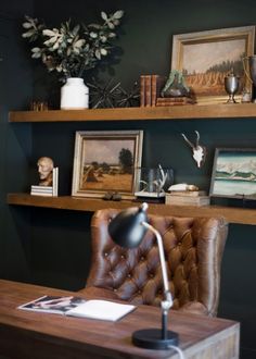 a desk with a chair, lamp and pictures on the shelves in front of it