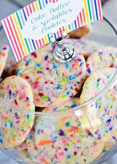 a glass bowl filled with cookies and sprinkles on top of a table