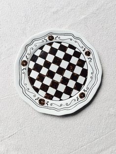 a black and white checkerboard plate with gold accents on the edges is shown