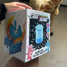 a person holding up a box with an image of a cartoon character on it and a cat in the background