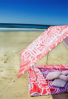 an open umbrella sitting on top of a sandy beach next to the ocean and blue sky