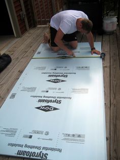 a man working on a large white sheet of paper that is laying on the floor