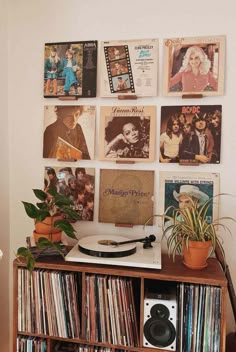 a record player sitting on top of a wooden table next to a wall filled with records