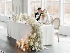 a bride and groom sitting at a table surrounded by candles