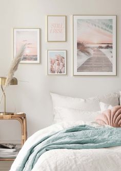 a bedroom with white walls and pictures on the wall above the bed, along with a wicker side table