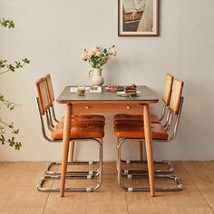 a table with chairs and a vase filled with flowers sitting on top of it next to a wall