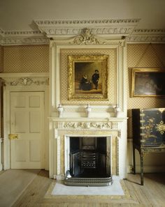 a room with a fireplace and paintings on the wall