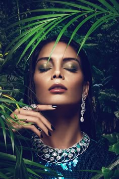 a woman with green eyeshades is posing for a photo in front of some plants