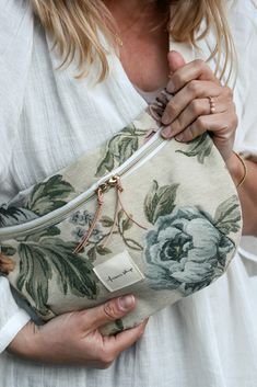 a woman is holding a floral purse with her hands in the pocket and showing it to the camera