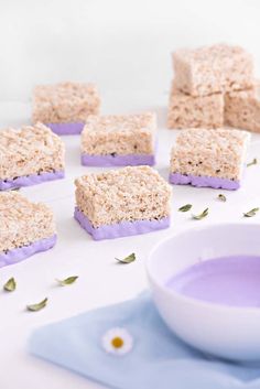 several pieces of rice krispy treats sitting on a table next to a bowl of blue liquid