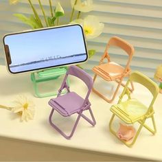 there are four miniature chairs next to each other with a cell phone in the middle