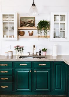 a kitchen with green cabinets and gold pulls on the handles, white walls and floor