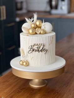 a white and gold birthday cake sitting on top of a wooden table