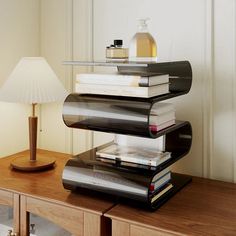 a stack of books sitting on top of a wooden table next to a lampshade