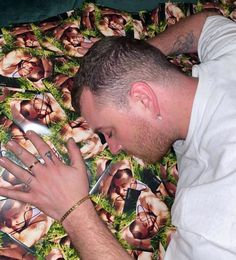 a man laying on top of a bed next to a pillow covered in pictures and tattoos