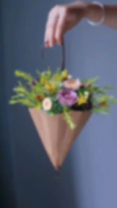 a woman holding a flower arrangement in her hand