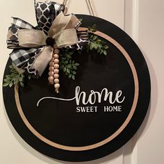 a home sweet home sign hanging on the front door with ribbon and pom - poms