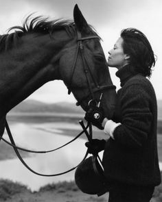 a woman standing next to a brown horse