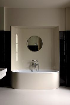 a white bath tub sitting under a round mirror