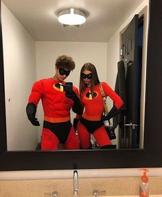 a man and woman dressed as the incredibles in front of a mirror looking at their cell phones