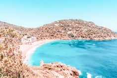 an aerial view of a beach with blue water and mountains in the background, taken from above