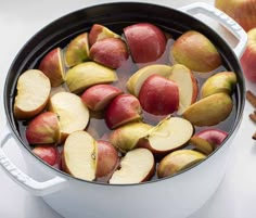 apples are in a pot with water and cinnamon sticks