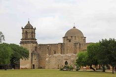 an old building with two towers and trees in the foreground